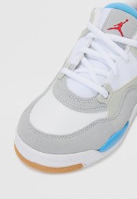 Sneaker grigia e bianca con tomaia in suede, dettagli blu e suola in gomma. Include lacci bianchi e un logo rosso sulla linguetta.