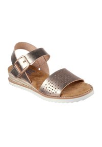 Sandalias metálicas en oro rosa con una correa perforada, hebilla ajustable, plantilla suave en tono bronceado y suela de goma blanca. Diseño texturizado en toda la superficie.