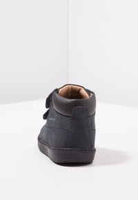 Bottine noire imperméable avec un extérieur en daim, bout rond, col rembourré et détails de couture contrastants en bleu. Design à lacets à l'avant.