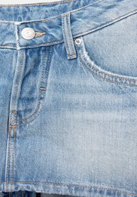 Shorts en denim bleu clair avec des coutures visibles, un bouton sur le devant et des détails déchirés sur le tissu. Design simple et décontracté.