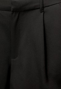 Czarne spodnie wykonane z gładkiej, miękkiej tkaniny, z przodu z plisami i płaskim paskiem w talii. Posiadają boczną kieszeń użytkową.