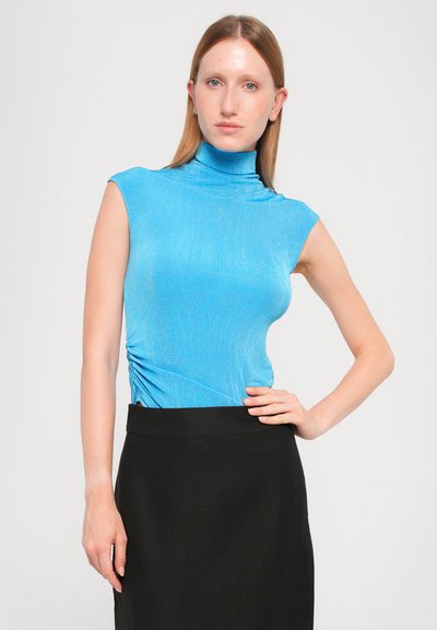 Vaaleansininen ilmanhiha turtleneck-toppi, jossa on rypistetty sivuyksityiskohta, yhdistetty mustan korkeavyötäröisen hameen kanssa. Sujuva rakenne, vartaloa myötäilevä malli.