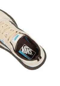 Vans tenisice s kremastim gornjim dijelom, tamnim potplatom i plavim akcentima. Imaju točkasti uzorak i "UltraCush" oznaku na ulošku.