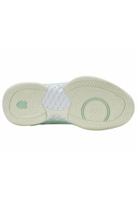 Semelle d'une chaussure de sport clair avec des motifs de grip texturés et des éléments de design circulaires sur un fond blanc.