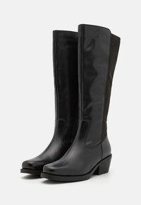 Knähöga svarta stövlar i läder och mocka med klack, som har en slät finish och vertikalt paneldesign.