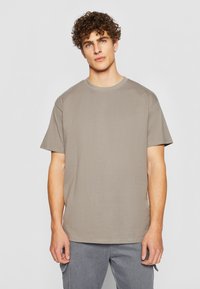 Kortermet t-skjorte med rund hals i en dempet beige farge. Myk bomullsstoff med avslappet passform, med minimale sømmer og uten grafikk.