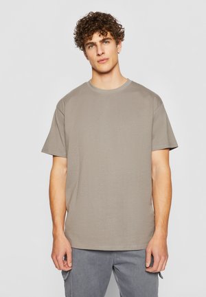 Korte mouwen, ronde hals t-shirt in een gedempte beige kleur. Zachte katoenstof met een relaxte pasvorm, met minimale naden en zonder graphics.