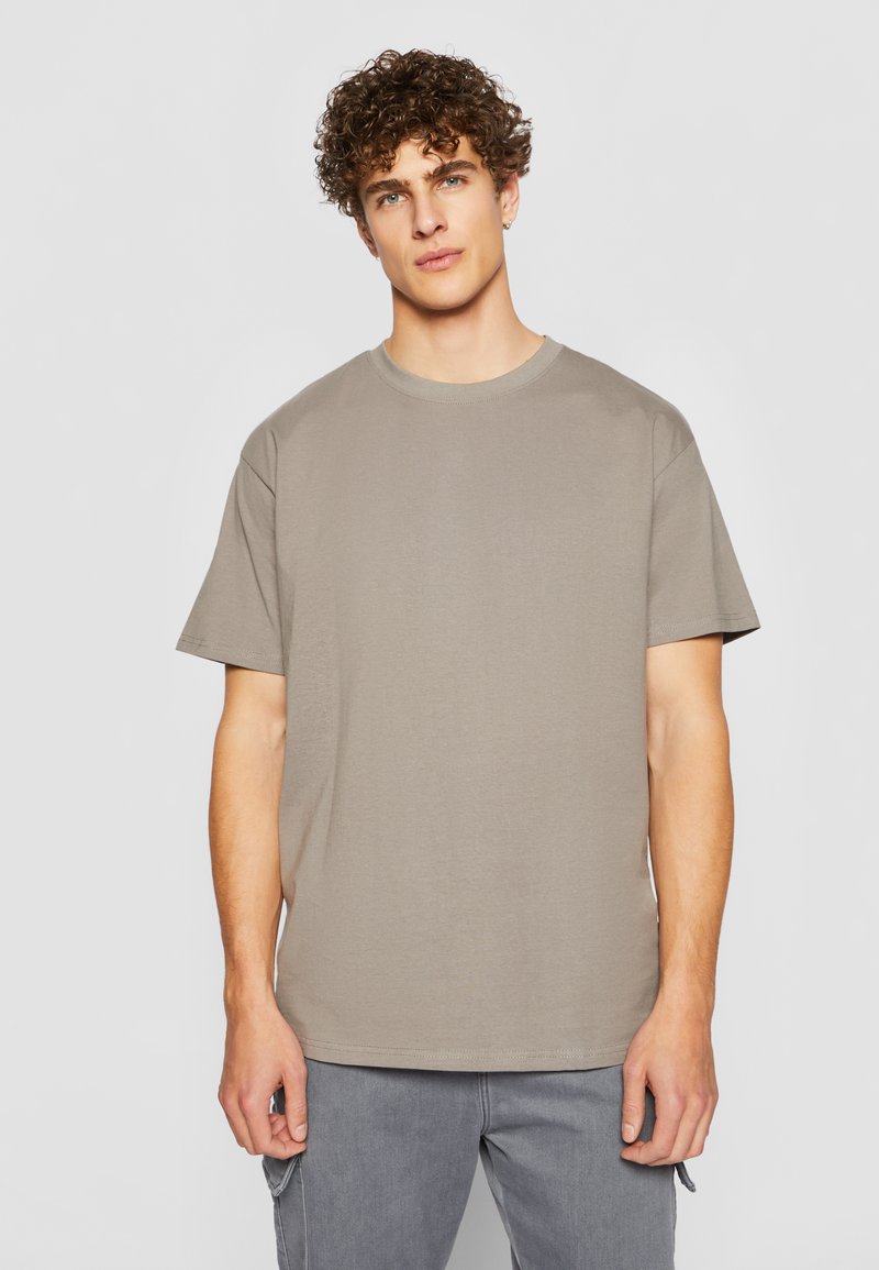 Kortermet t-skjorte med rund hals i en dempet beige farge. Myk bomullsstoff med avslappet passform, med minimale sømmer og uten grafikk.
