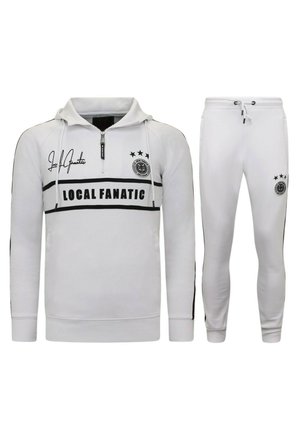 Witte rits hoodie met zwarte accenten, voorzien van de tekst "LOCAL FANATIC", een logo en drie sterren. Bijpassende witte fitted broek met zwarte details.
