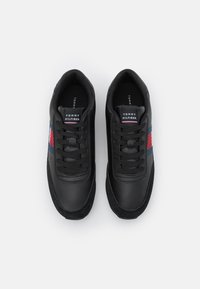 Sneaker in pelle nera con accenti in suede nero testurizzato, caratterizzate da un logo a strisce rosse e blu sul lato e lacci neri.