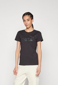 Camiseta negra de manga corta con un logo de "PUMA" en textura gris claro y gráfico de pantera. Cuello redondo y tejido de algodón suave.