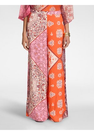 Lang nederdel med pink, rød og hvid patchwork paisley og blomsterprint, båret med guldbangles på højre håndled.