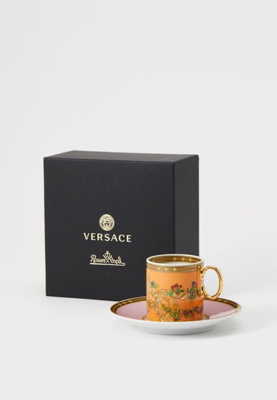 Κούπα καφέ από πορσελάνη σε πορτοκαλί χρώμα με λουλουδάτα σχέδια και χρυσές λεπτομέρειες, συνοδευόμενη από ένα λευκό και ροζ πιατάκι, παρουσιάζεται σε μαύρο κουτί.