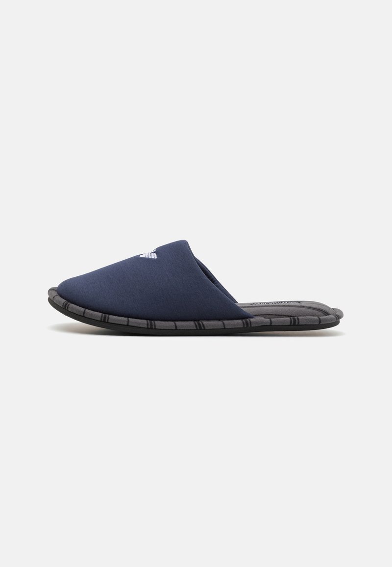 Pantofole navy slip-on con upper in tessuto morbido, suola nera testurizzata e minimo branding davanti. Profilo basso con punta arrotondata.