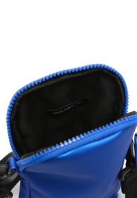 Blå axelväska med svart innerfoder, öppen dragkedja och synlig Misako-märke inuti.