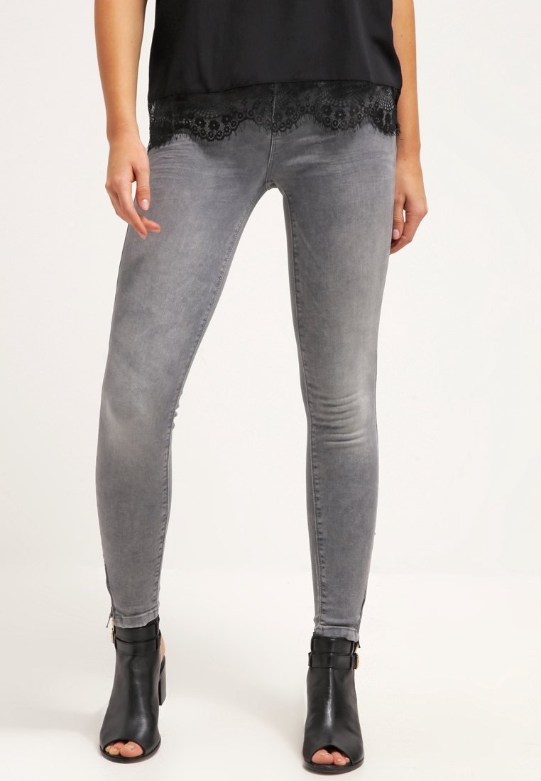 Jeans ajustados de mezclilla gris con una cintura de altura media, que presentan una textura suave y un ligero desgaste, combinados con una blusa negra con encaje.