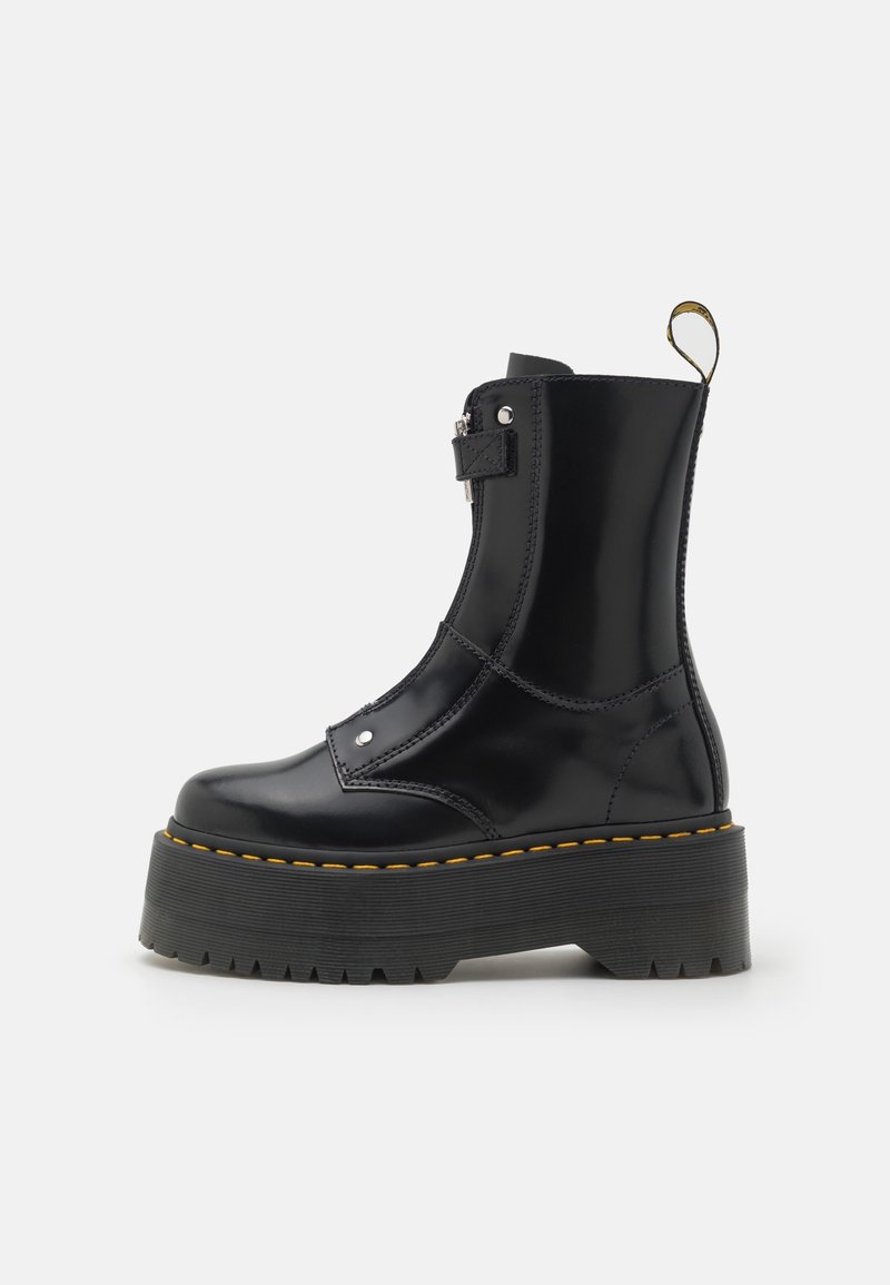 Botte plateforme en cuir noir brillant avec semelle épaisse rainurée, fermeture éclair latérale, détail de sangle et couture jaune autour du bord de la semelle.