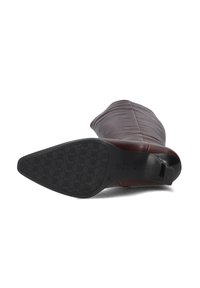 Bordeaux leren boot met een taps toelopend ontwerp, een gladde textuur en een zwarte rubberen loopzool met een hexagonaal patroon.