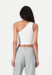 Witte geribbelde cropped top met een schouderontwerp, gecombineerd met lichtblauwe en witte gestreepte hoge taillebroek met achterzakken.