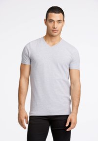 Szary, krótki rękaw, t-shirt w serek wykonany z gładkiego, lekkiego materiału, o luźnym kroju i czystych szwach, zestawiony z czarnymi spodniami.