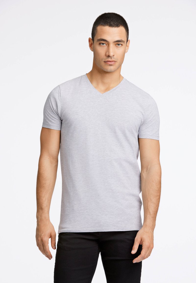 Szary, krótki rękaw, t-shirt w serek wykonany z gładkiego, lekkiego materiału, o luźnym kroju i czystych szwach, zestawiony z czarnymi spodniami.