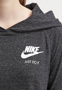 Dark gray hoodie made of textured fabric, featuring a white Nike logo and the phrase "JUST DO IT" in bold lettering on the front.