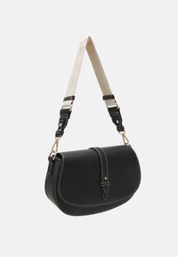 Musta nahkainen olkalaukku, jossa on kaareva muoto, valkoiset ompeleet ja irrotettava kerma valkoinen olkahihna. Laukussa on kultaiset metalliosat ja läppä suljenta.