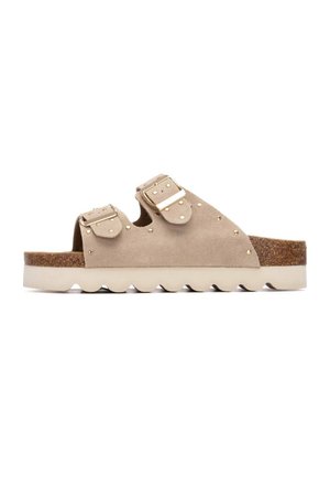 Sandalias de ante beige con dos hebillas ajustables, detalles con tachuelas, suela texturizada de corcho y goma, y diseño ondulado en la suela exterior.