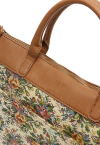 Sac en toile avec des accents en cuir brun, design en tapisserie florale dans des nuances de jaune, rouge et vert, présentant une fermeture à glissière et des poignées robustes.