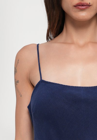 Camiseta de tirantes ajustables finos en azul marino, con un escote cuadrado, hecha de un tejido suave y texturizado; presenta una silueta ajustada.