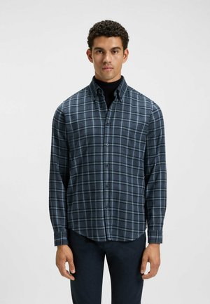 Camisa de franela para hombre en cuadros azul oscuro y gris. Cuello con botones, mangas largas y dobladillo redondeado. Textura suave con un ajuste relajado.