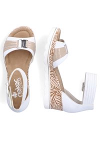 Sandales compensées blanches et beiges avec des brides brillantes, une boucle décorative et une plateforme texturée avec un design à motifs.