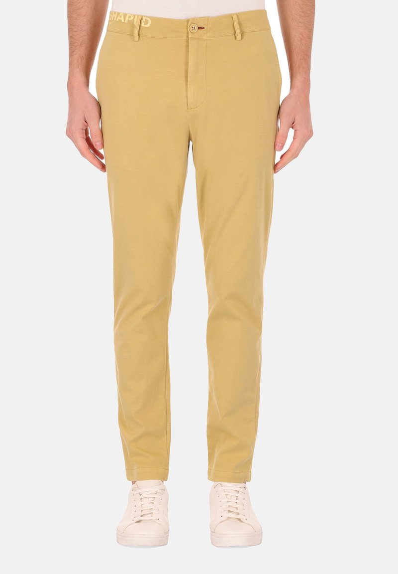 Geel katoenen chinos met een rechte pasvorm, riemlussen, knoopsluiting en een subtiel logo op de tailleband. Gemaakt in combinatie met witte sneakers.