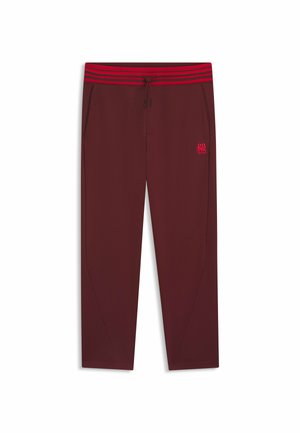 Burgundy sweatpants with a red-striped elastic waistband. Features side pockets and a small embroidered logo on the left thigh.