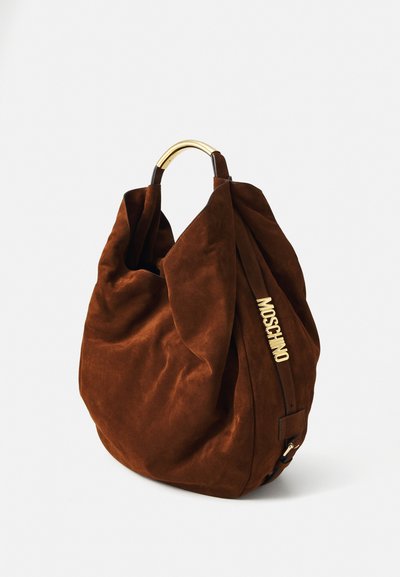 Sac hobo en daim marron avec quincaillerie dorée, une anse courbée et un logo visible sur le côté. Texture douce avec un design souple et décontracté.