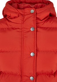 Rød pufferjakke med metallisk trykknapper, høy krage og quiltet tekstur. Stoffet ser glatt ut og er vannavstøtende.