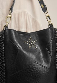 Schwarze Lederhandtasche mit sternförmiger Naht und kleinen goldenen Nieten, ausgestattet mit goldenen Verschlüssen und einem strukturierten Quasten-Detail an der Seite.