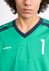 Green Adidas jersey with a V-neck, navy accents, white number "1," and logo on the left chest. Features a textured fabric.