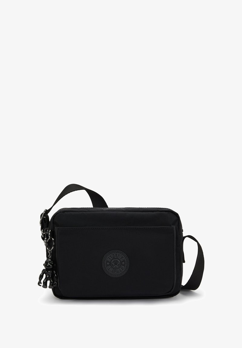 Borsa a tracolla nera in tessuto, di forma rettangolare, con tasca frontale con zip e un'etichetta con logo. Presenta una tracolla staccabile e un charm decorativo.