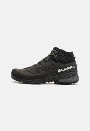 Black hiking shoe with suede and mesh upper, featuring green laces, rugged rubber sole, and embossed detailing. Brand name displayed.