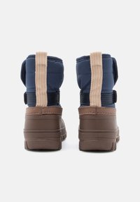 Et par brune og navy vinterstøvler med beige pull-tabs og sorte stropper, vist fra bagsiden på en hvid baggrund.