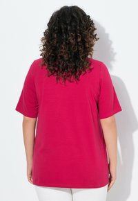 T-shirt magenta à manches courtes avec une coupe décontractée, texture lisse et ourlet droit. Stylé avec un design uni, sans motifs ni accents visibles.