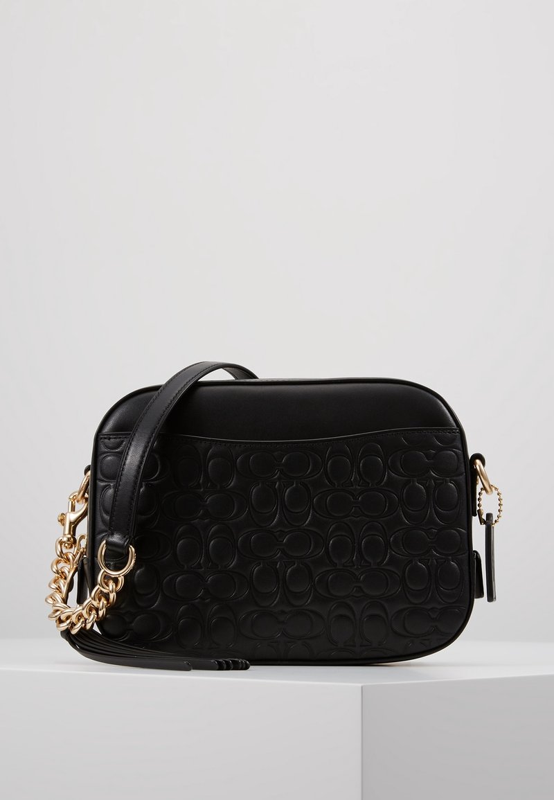 Musta nahkainen olkalaukku, jossa kohokuvioitu kuvio, kultainen ketjusomiste, suorakulmainen muoto ja irrotettava olkahihna.