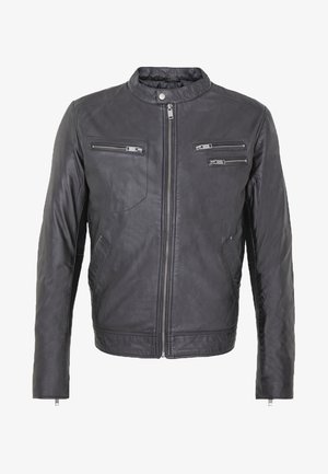 Chaqueta de cuero negro con cuello alto, cierre frontal con cremallera, tres bolsillos con cremallera y una textura suave. Presenta mangas ajustadas y corte recto.