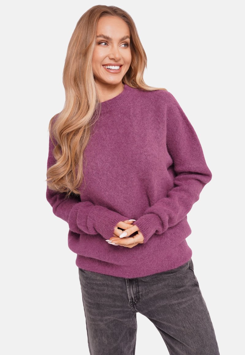 Purple wool sweater with a round neckline, dropped shoulders, and ribbed cuffs, paired with dark gray jeans. Soft texture and relaxed fit.