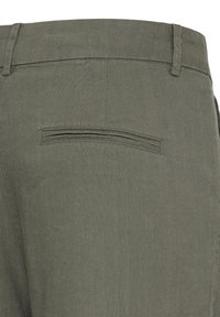Dos d'un pantalon vert olive montrant la ceinture, les passants de ceinture et une poche passepoilée simple avec des détails de couture.