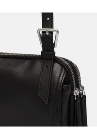 Borsa a tracolla nera in pelle con zip e hardware argentati. Caratterizzata da una tracolla regolabile e materiale testurizzato. Forma rettangolare compatta.