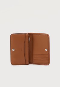 Καφέ δερμάτινο πορτοφόλι ανοιχτό που δείχνει θήκες για κάρτες, φερμουάρ για κέρματα και κλεισίματα με κουμπί σε απλό φόντο.