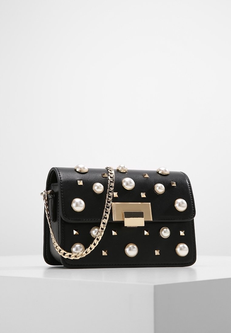 Borsa a tracolla in pelle nera decorata con borchie rotonde e a piramide, hardware dorato e una tracolla a catena. Forma rettangolare con chiusura a pattina.