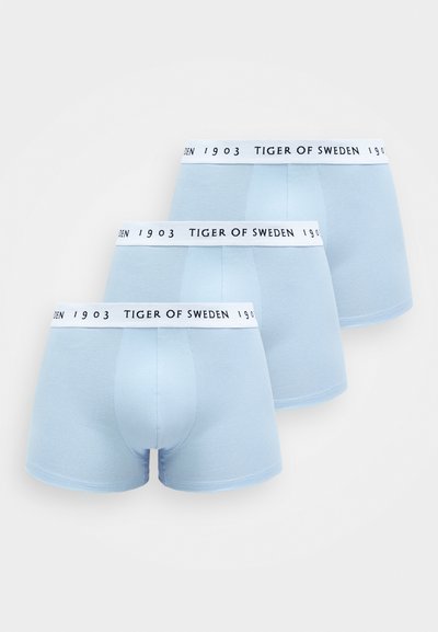 Três pares de boxers azul claro com uma faixa elástica branca que apresenta "TIGER OF SWEDEN 1903" em texto preto. Textura de tecido suave.
